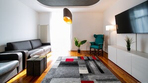 Un salon moderne avec un canapé, un fauteuil, un téléviseur et une plante.
