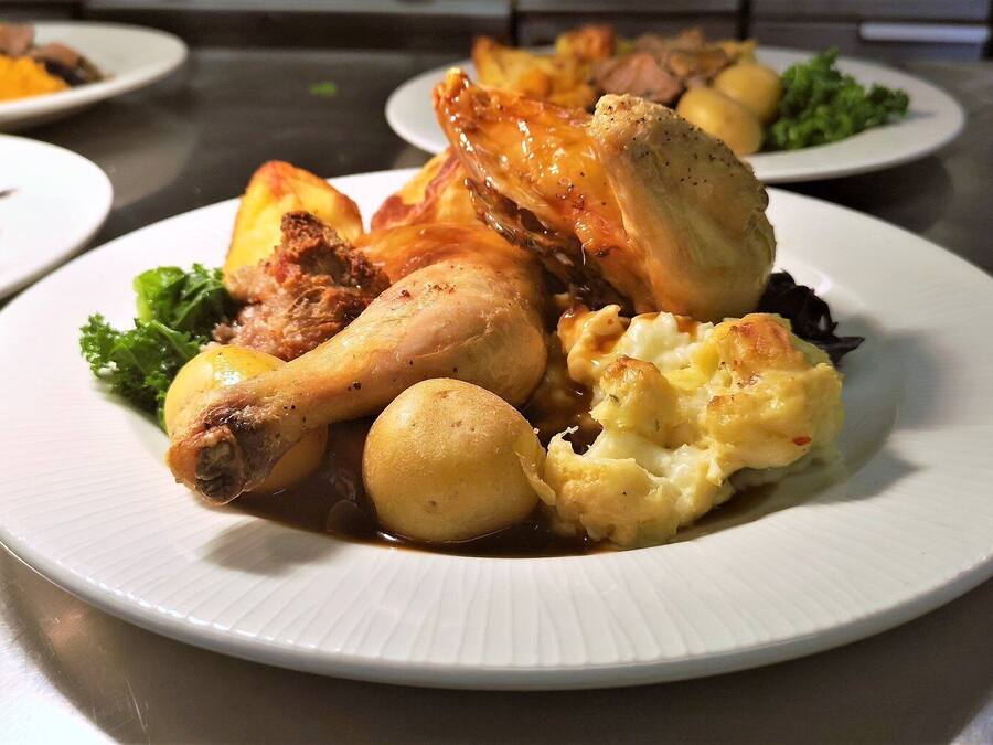 Un plato con pollo asado, papas y una guarnición de verduras.