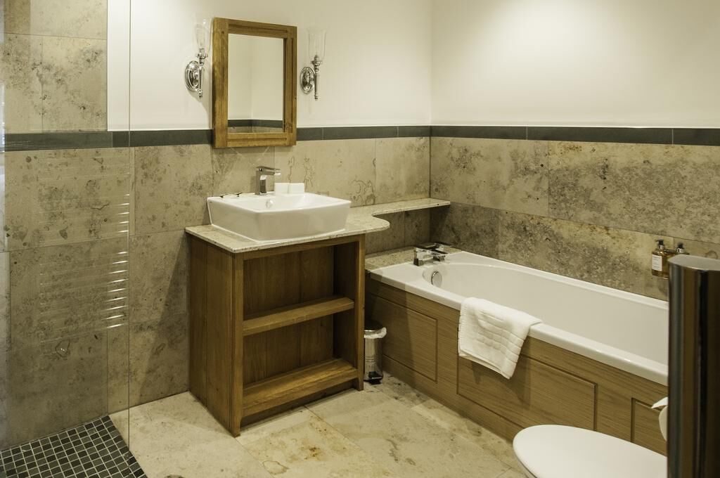 A bathroom with a sink, vanity, bathtub, and toilet.