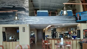 Un restaurante con zona de bar, asientos y una pantalla de televisión mostrando un noticiero.