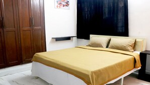 A bedroom with a bed, wooden wardrobe, and a painting on the wall. - LRH EasyStay 4 (Pune)