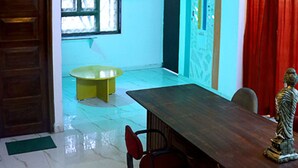 A room with a wooden door, a green chair, a wooden table, and a statue. - LRH EasyStay 4 (Pune)