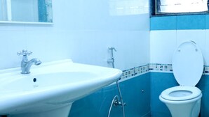 A bathroom with a white sink, a toilet, and blue tiled walls. - LRH EasyStay 4 (Pune)