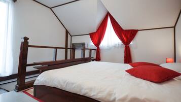 A bedroom with a wooden bed, white bedding, and red curtains.