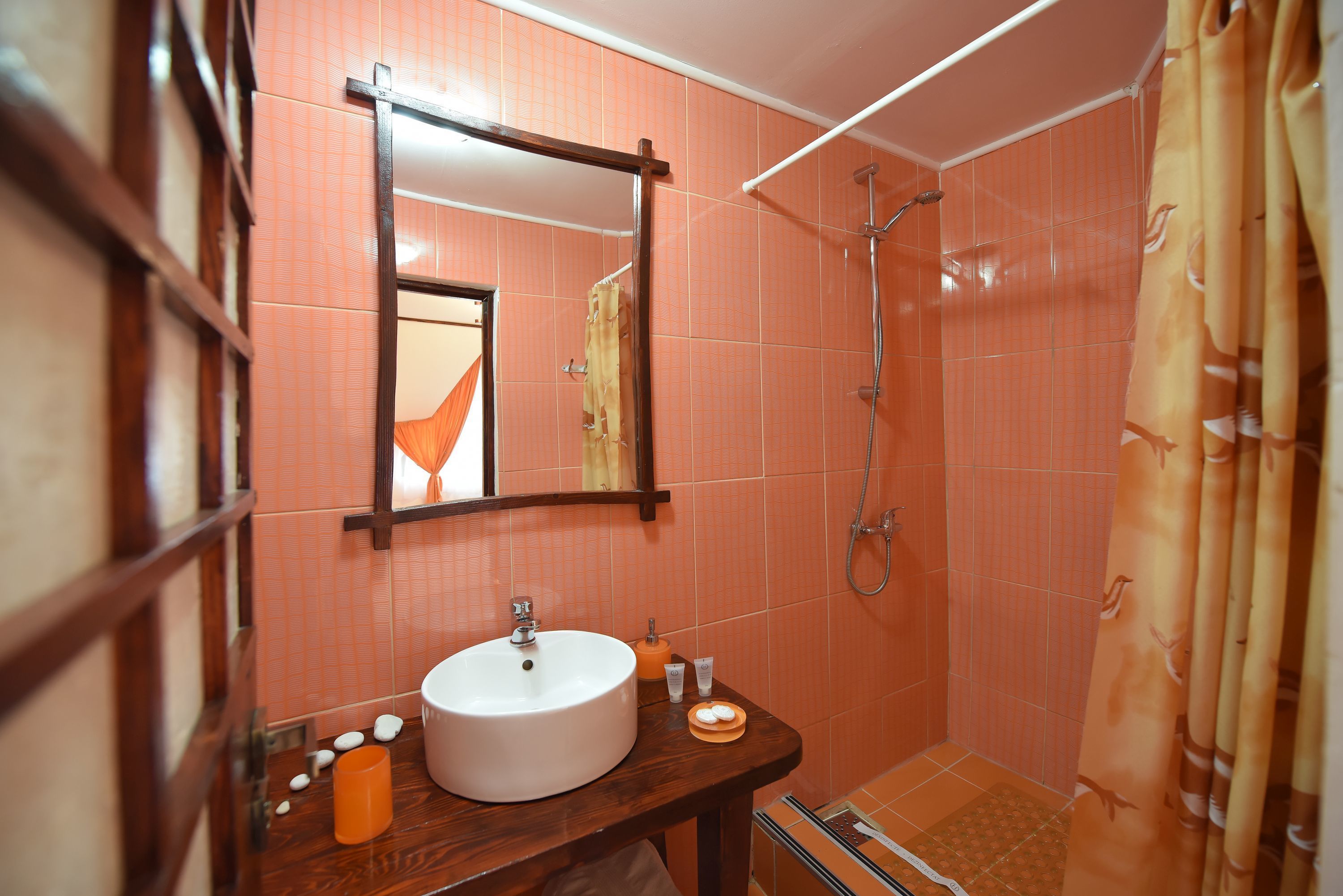 Un baño con tocador de madera, un espejo grande, un lavamanos blanco y una zona de ducha.