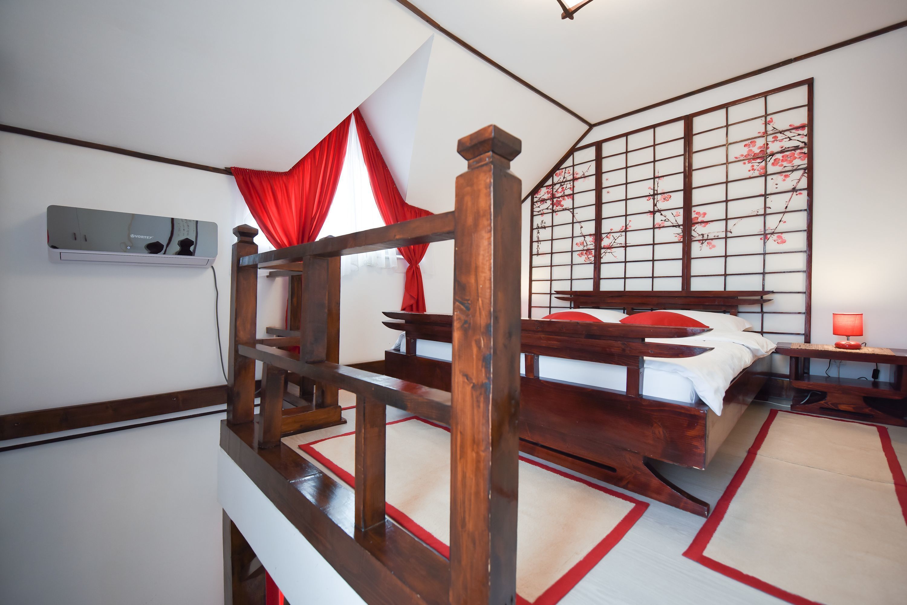 Una camera da letto tradizionale in stile giapponese, con un letto di legno, tatami, un sipario rosso e bianco e un paravento shoji con fiori di ciliegio.