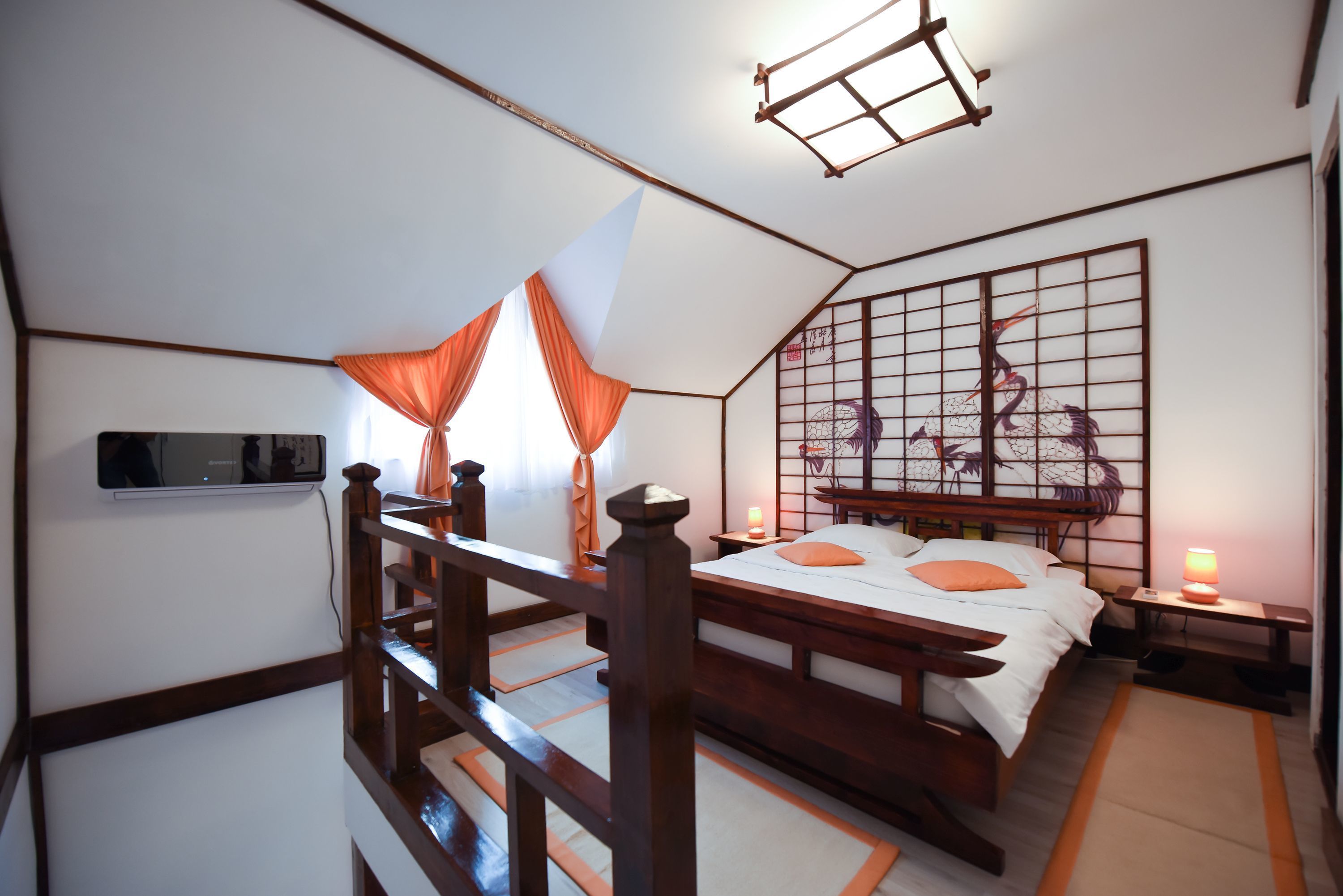 Una camera da letto in stile tradizionale giapponese con pavimento in tatami, un letto basso in legno, un pannello scorrevole shoji e un televisore a parete.