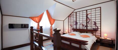 A traditional Japanese-style bedroom with tatami flooring, a low wooden bed, a shoji screen, and a mounted television.