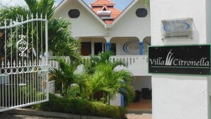 Villa Citronella, un bâtiment blanc doté d’une entrée sécurisée par un portail, de palmiers et d’un panneau indiquant qu’il s’agit du centre océanographique Carabao.