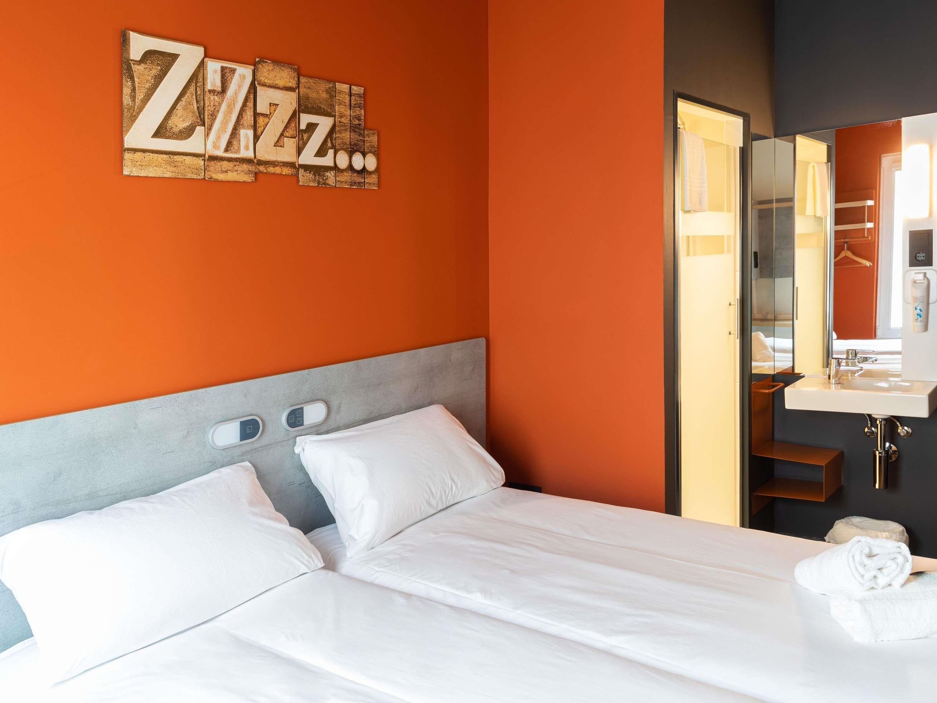Ein Hotelzimmer mit Bett, Spiegel, Waschbecken und Wand mit 'Zzz'-Dekoration.