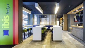 A modern interior with a reception desk, seating area, and a view of the outside. - ibis budget Bilbao City (Bilbao)