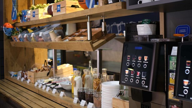 A coffee station with a coffee machine, cups, and various coffee pods.