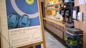A sign with breakfast hours and a store interior with shelves and a counter.