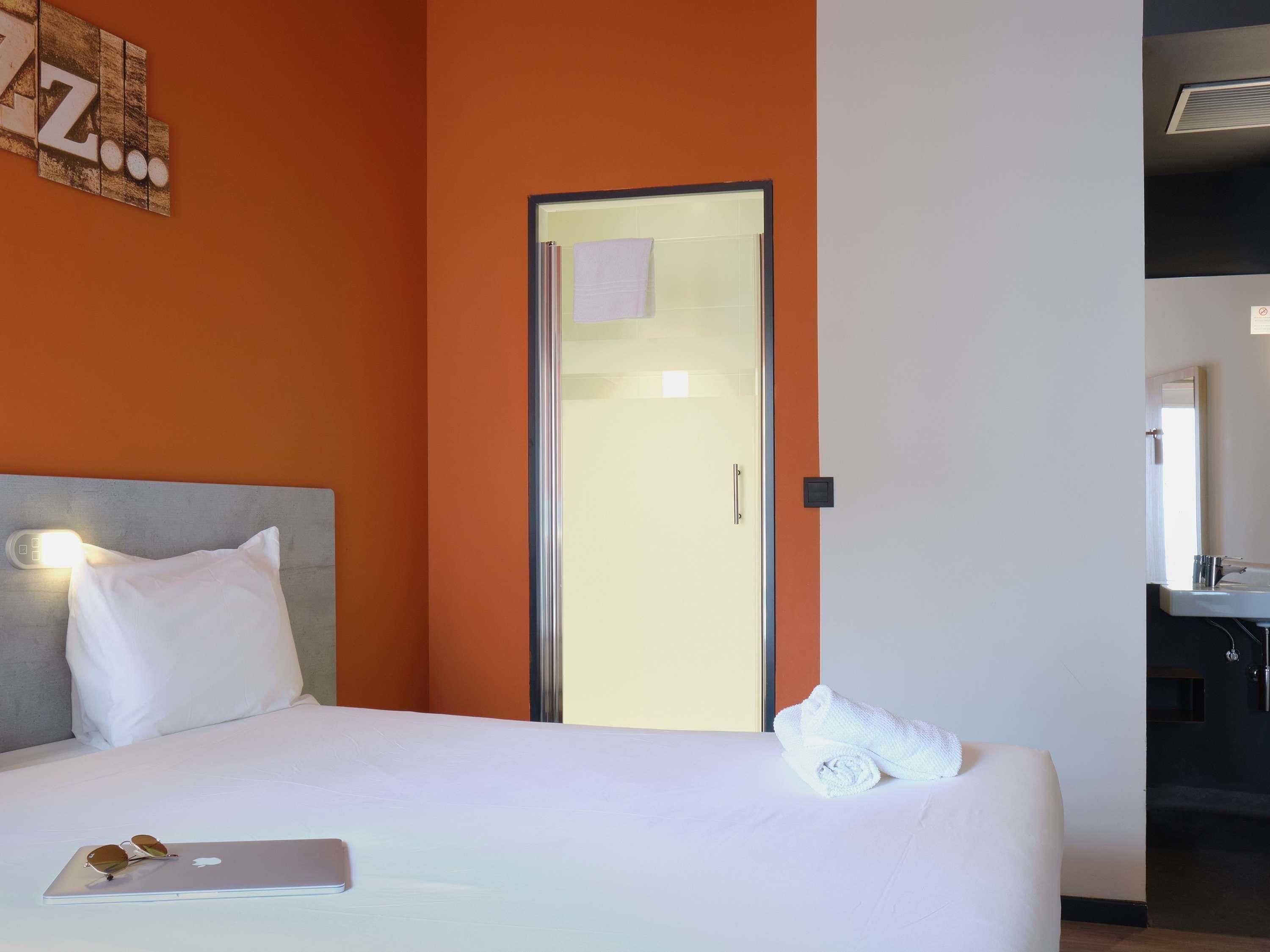 A hotel room with a bed, a laptop, and a towel on the bed.