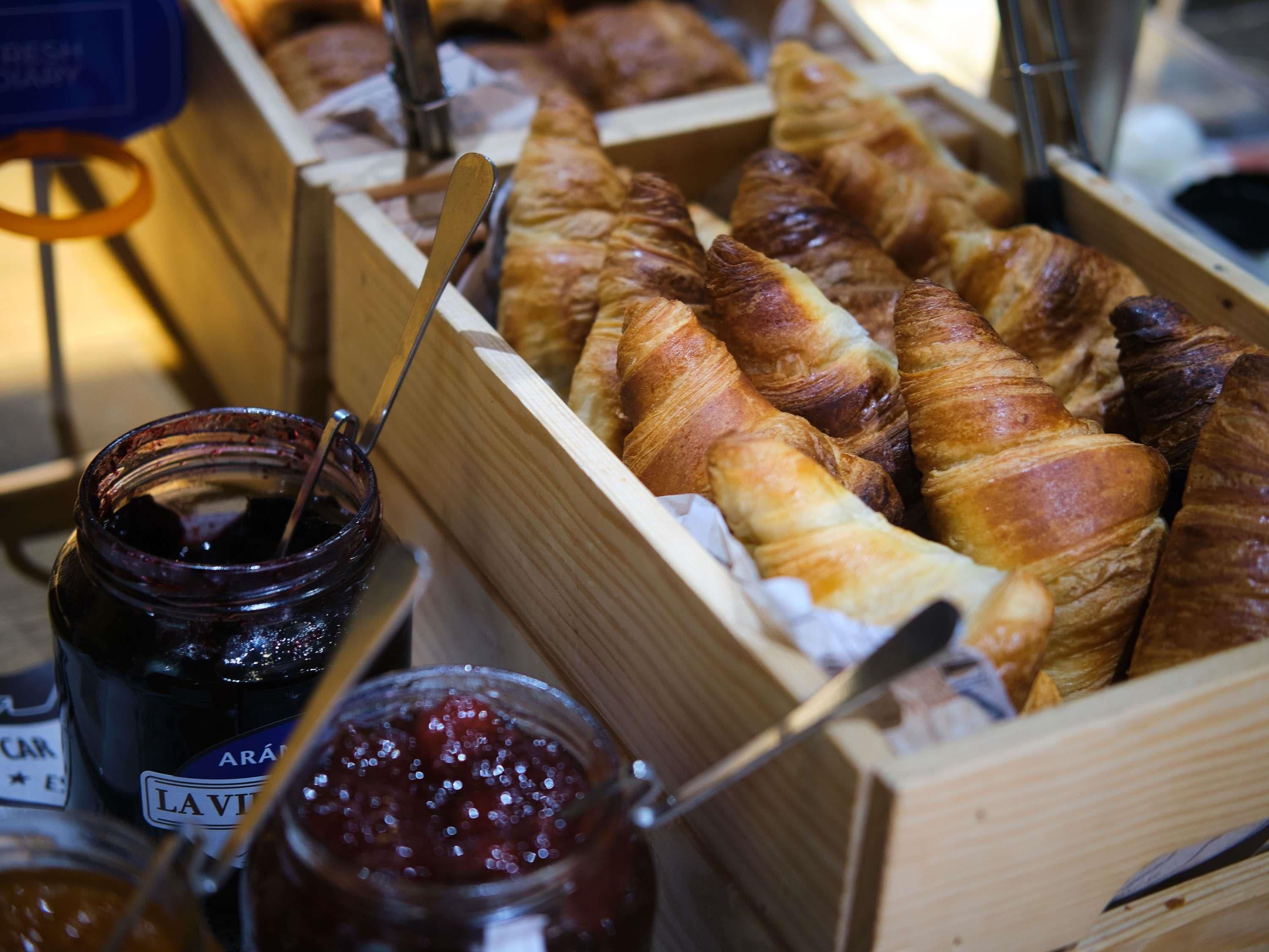 Una presentación de croissants y frascos de mermelada.
