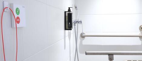 A bathroom with a shower, a hand dryer, and a towel rack.