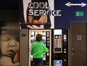 A person in a green shirt interacting with a vending machine in a hotel lobby. - ibis budget Bilbao City (Bilbao)