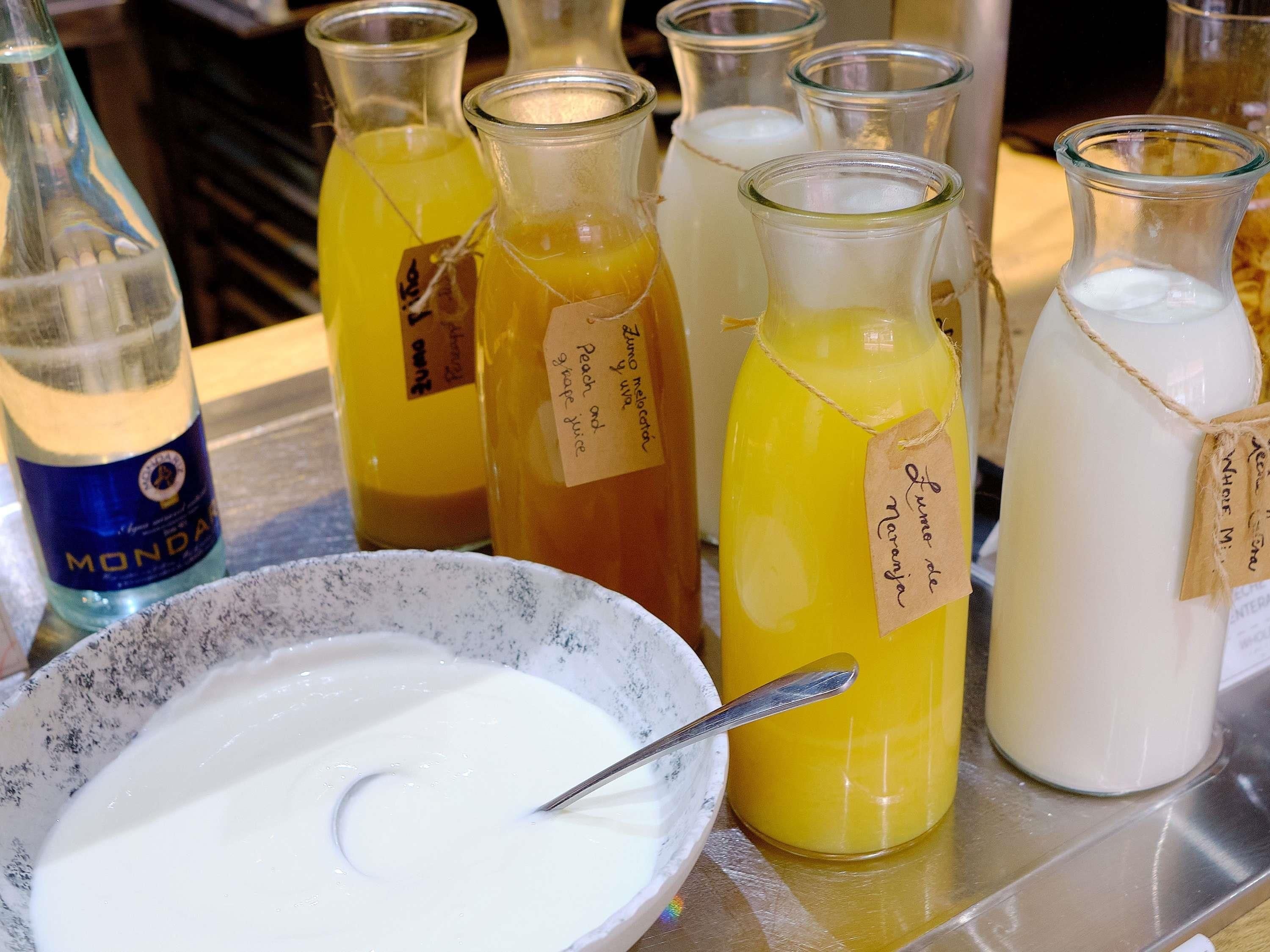Varias botellas de vidrio con etiquetas, un bol de líquido blanco y una cuchara.
