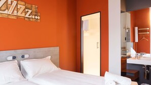 A hotel room with a bed, a bathroom, and a wall with a sign. - ibis budget Bilbao City (Bilbao)