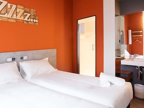 A hotel room with a bed, a bathroom, and a wall with a sign. - ibis budget Bilbao City (Bilbao)