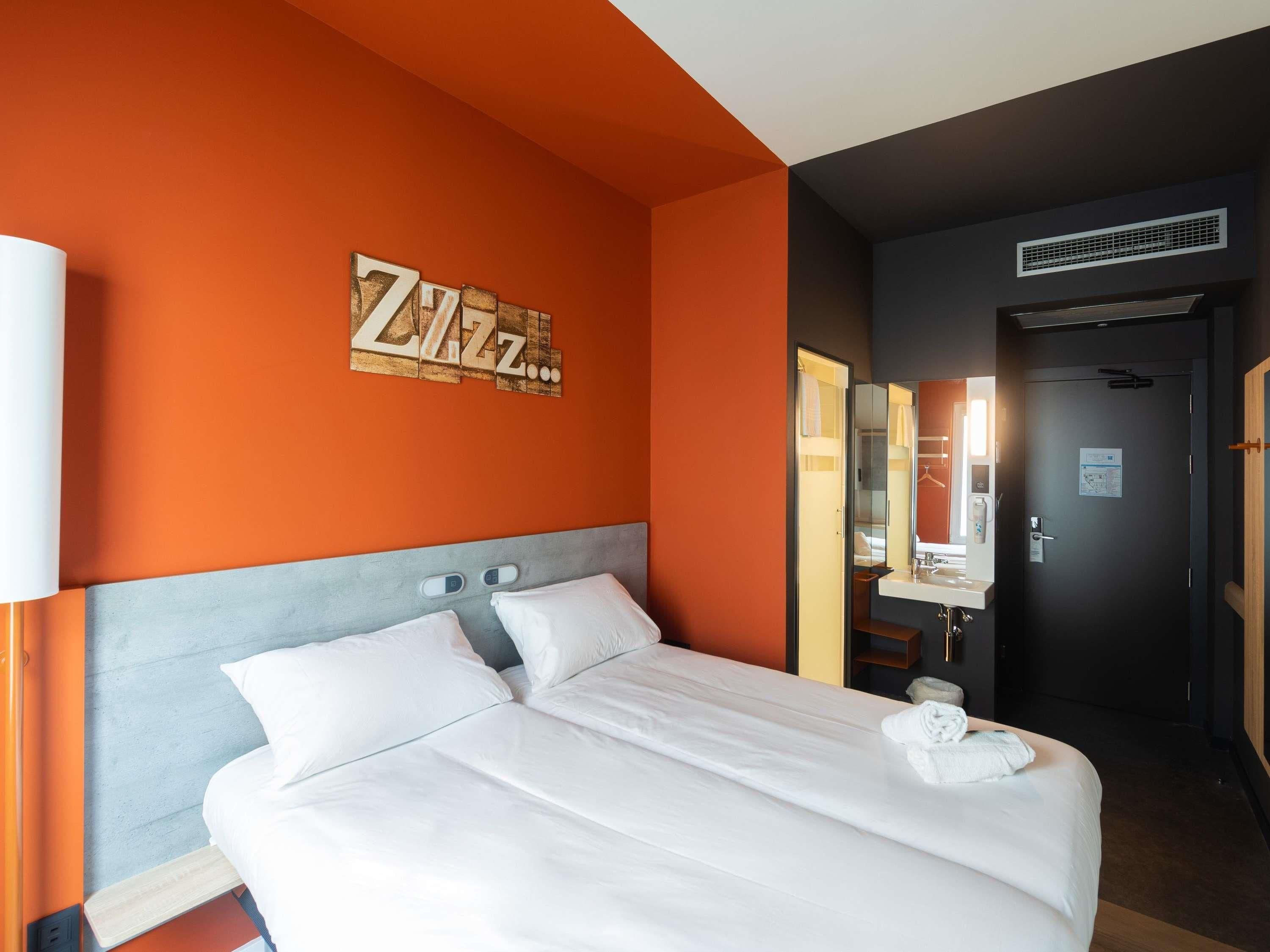 Hotelkamer met groot bed, hoofdeinde, wanddecoratie, badkamer met spiegel en een deur.