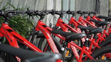 Una hilera de bicicletas rojas con la marca 'Swissotel', estacionadas junto a una pared de madera.