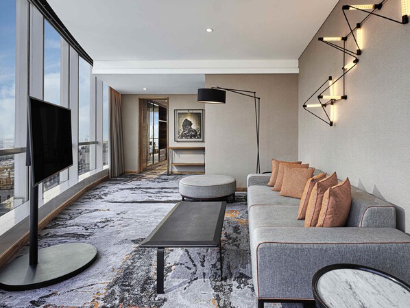 Un salon moderne avec un grand téléviseur, un canapé, une table basse et un tapis à motifs.