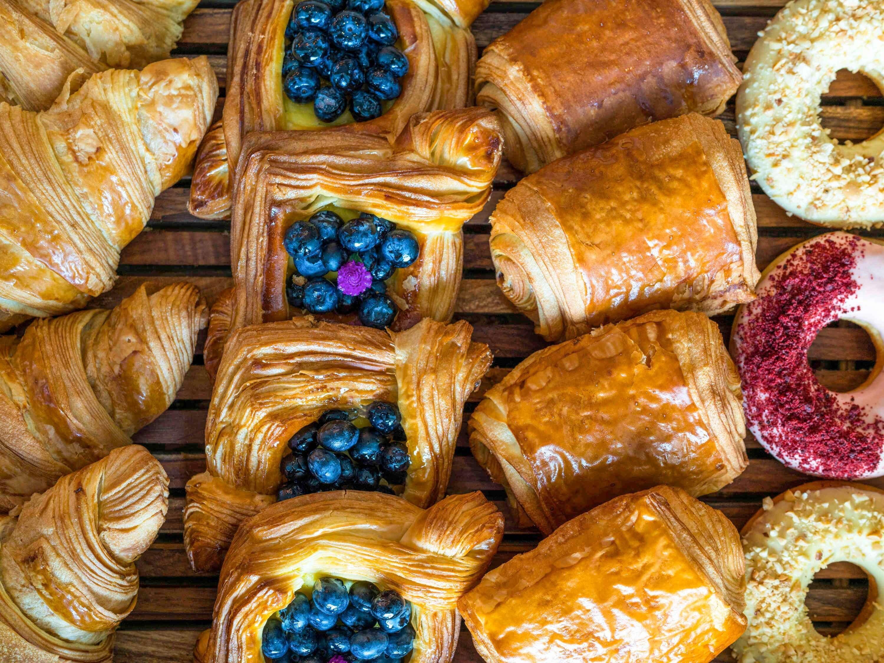On y trouve une variété de viennoiseries, notamment des croissants et un beignet recouvert de vermicelles roses.