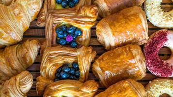 On y trouve une variété de viennoiseries, notamment des croissants et un beignet recouvert de vermicelles roses.
