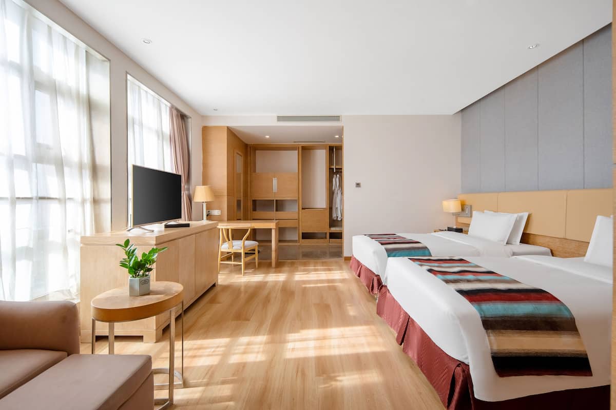 Ein Hotelzimmer mit Bett, Schreibtisch, Fernseher und einem kleinen Tisch mit Pflanze.