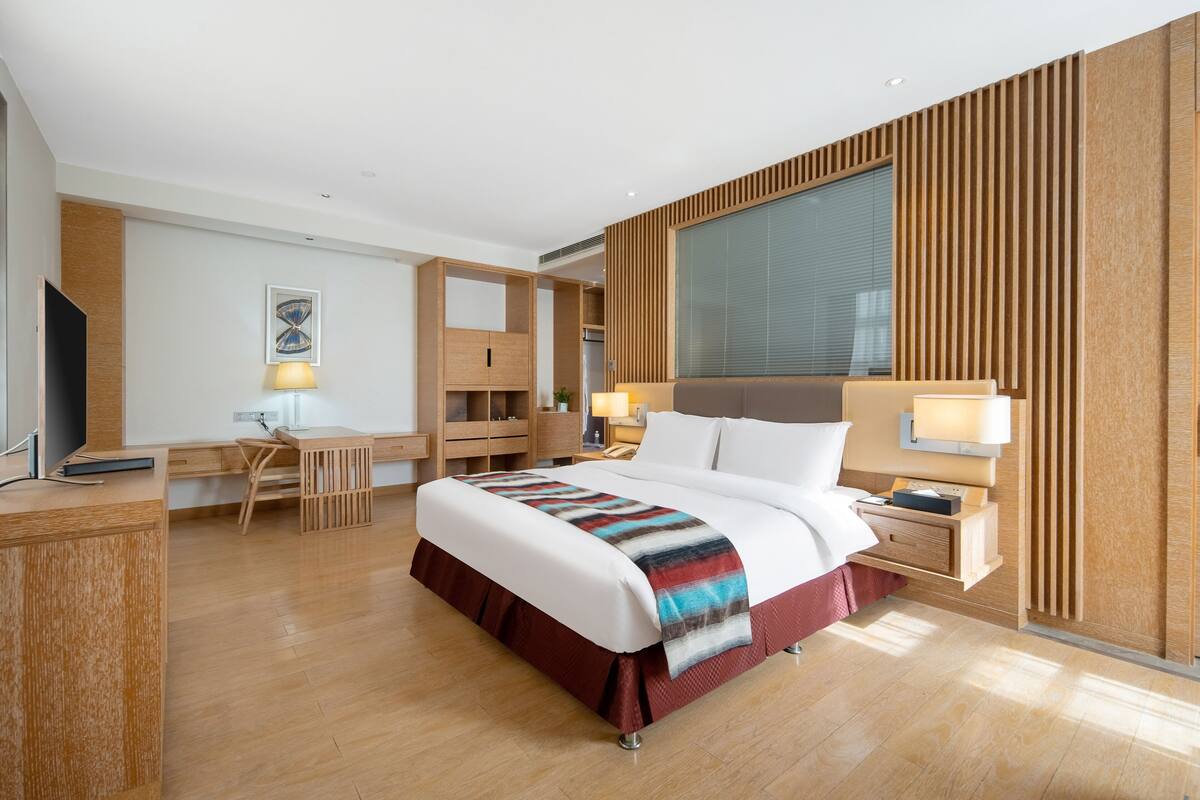 Ein modernes Hotelzimmer mit einem großen Bett, einem Schreibtisch und einem Fernseher.