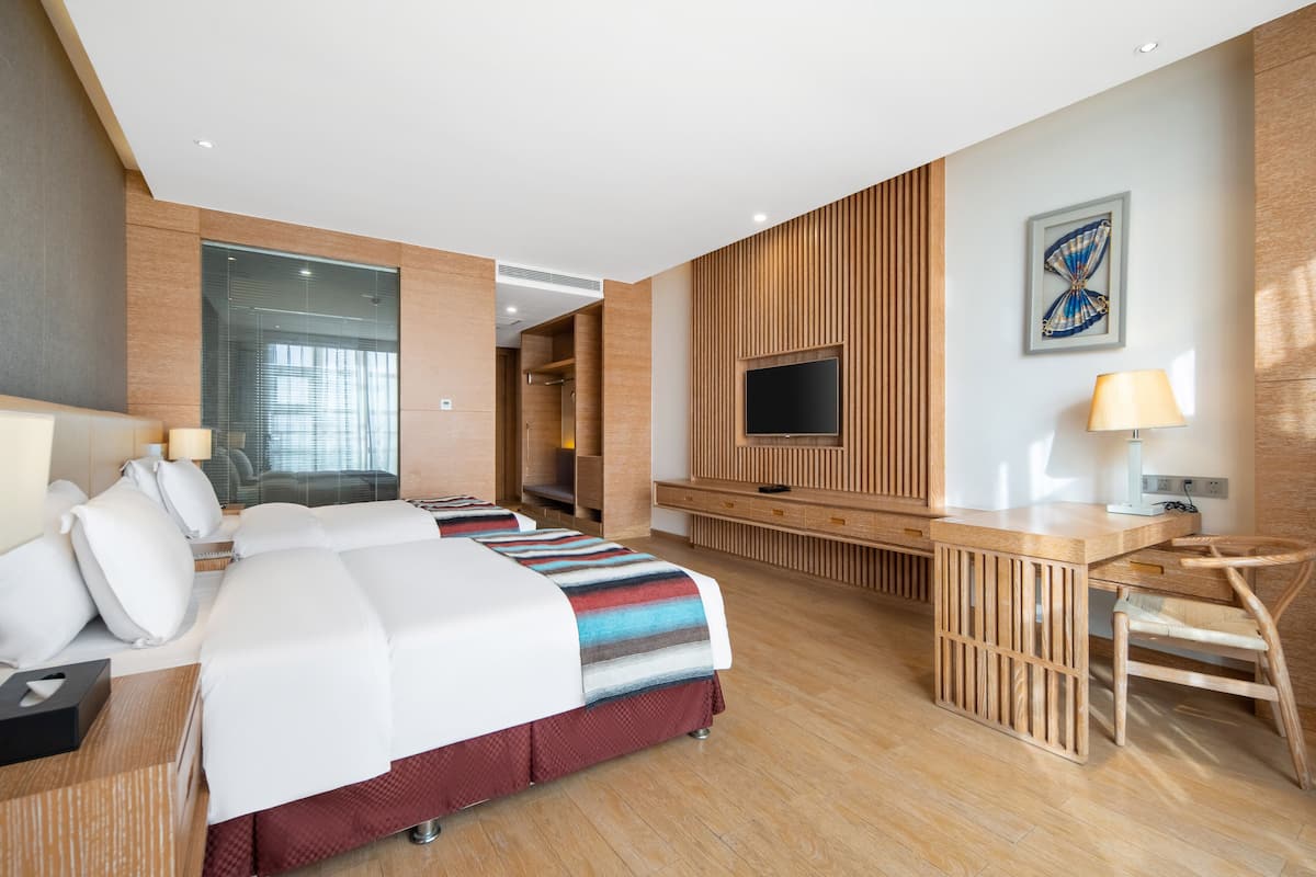 Ein modernes Hotelzimmer mit einem großen Bett, einem Schreibtisch, einem Fernseher und einer Sitzecke.