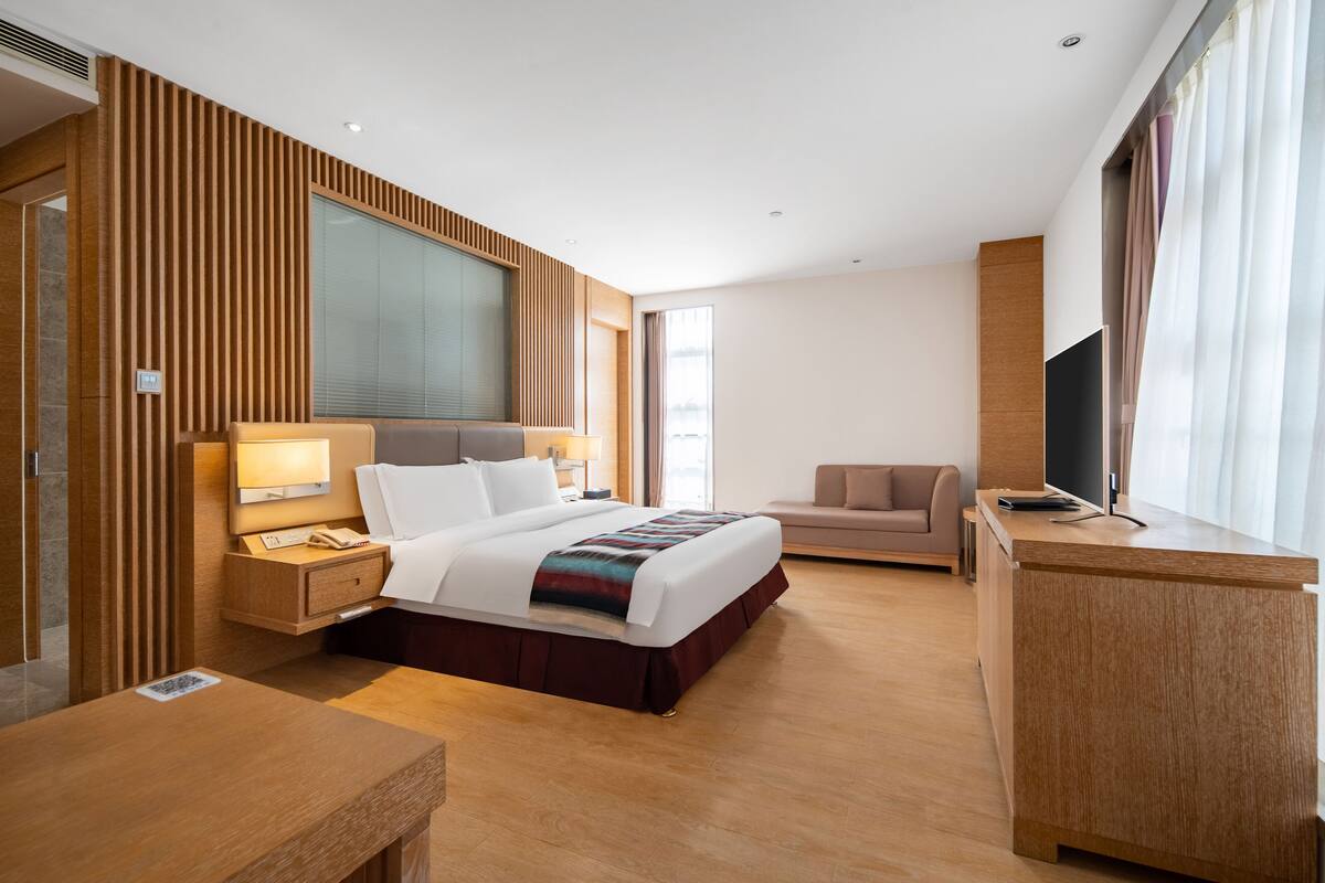 Ein modernes Hotelzimmer mit einem großen Bett, einem Nachttisch und einem Schreibtisch.