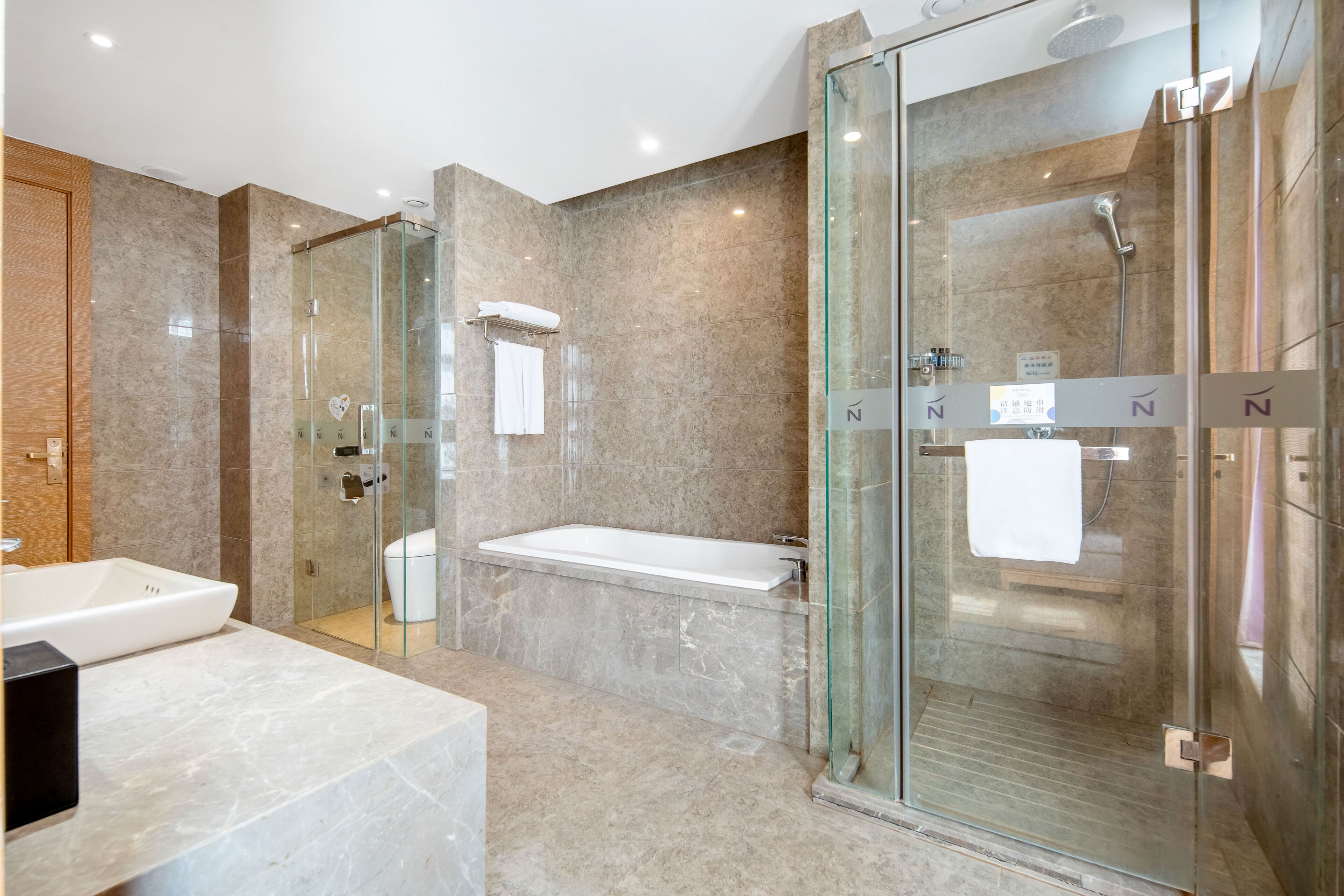 Une salle de bain moderne dotée d’une douche à parois de verre, d’une baignoire et de toilettes.