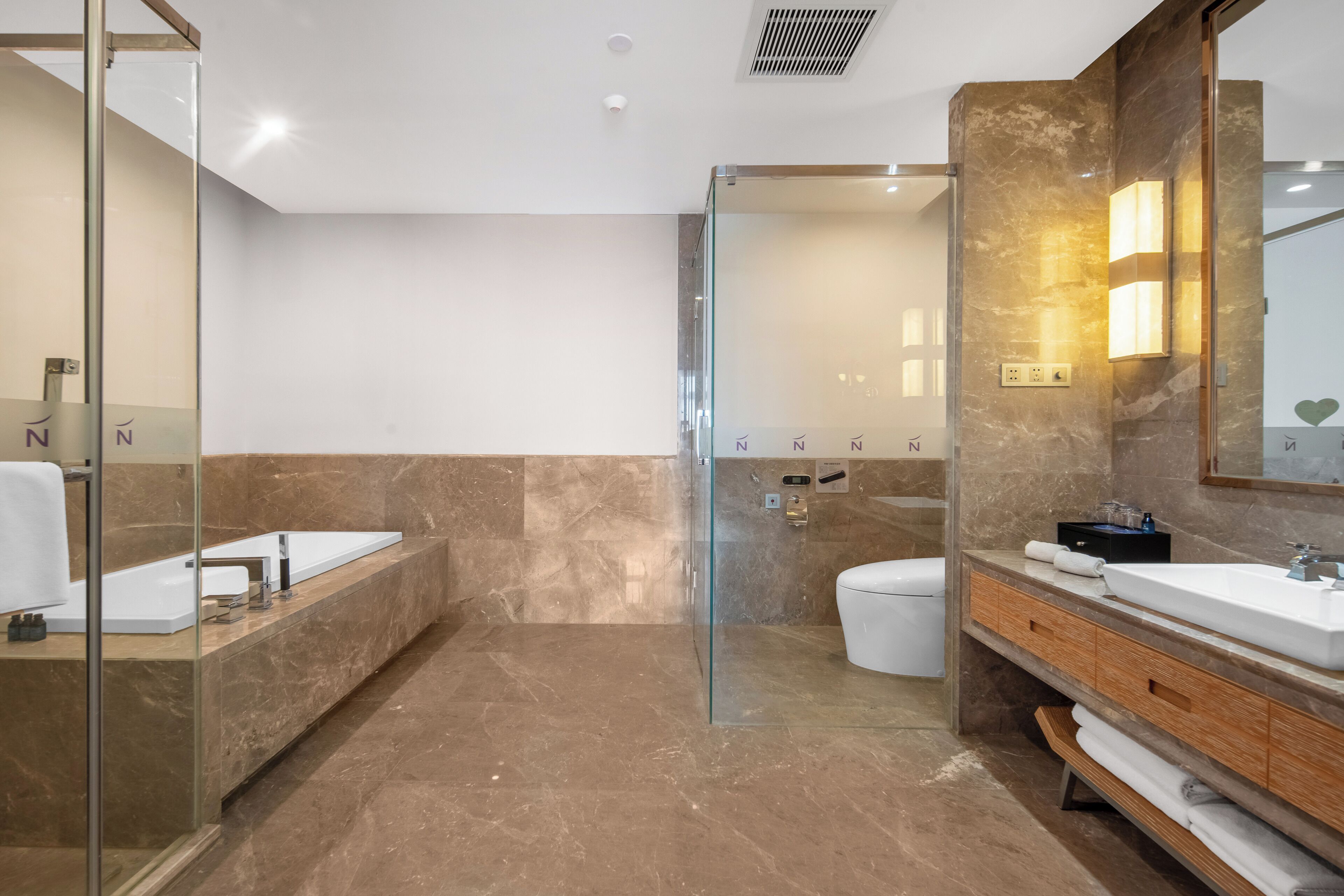 A modern bathroom with a glass shower enclosure, a large mirror, and a vanity with a sink and storage.