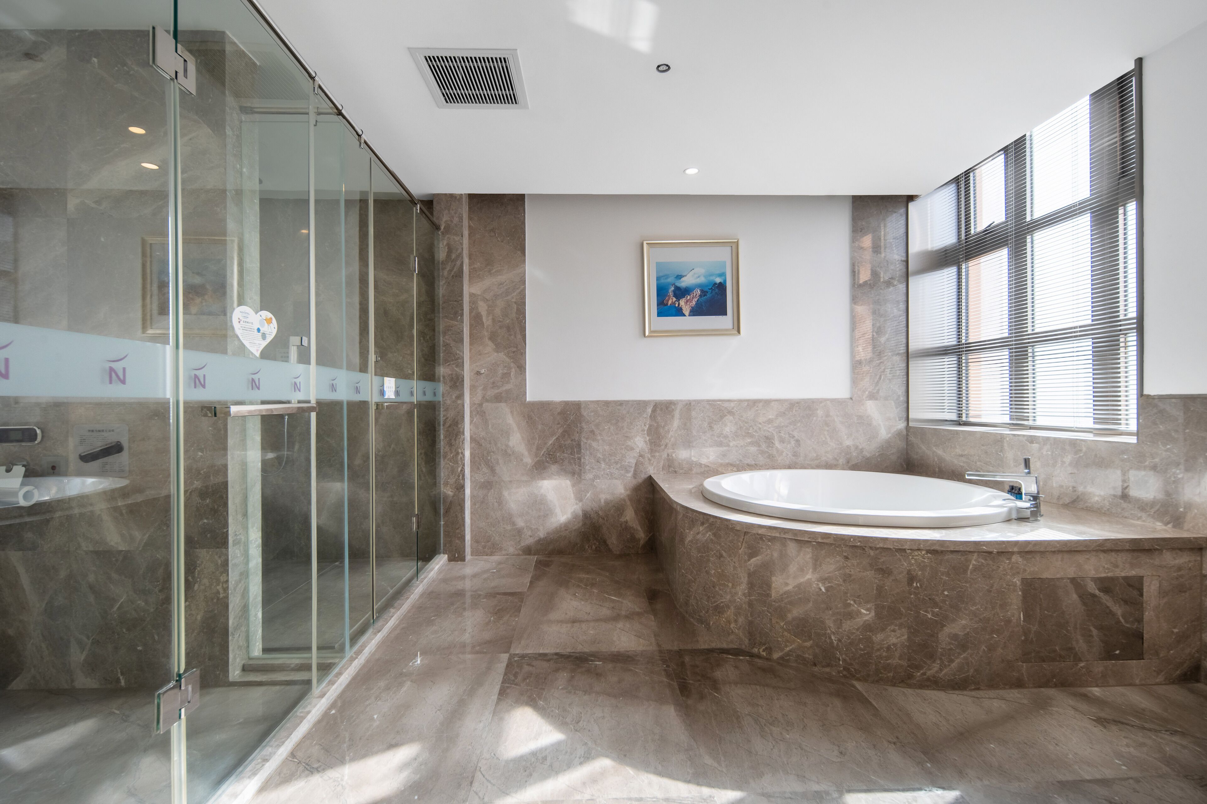 A modern bathroom with a glass-enclosed shower, a freestanding bathtub, and a marble floor.