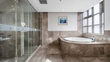 A modern bathroom with a glass-enclosed shower, a freestanding bathtub, and a marble floor.