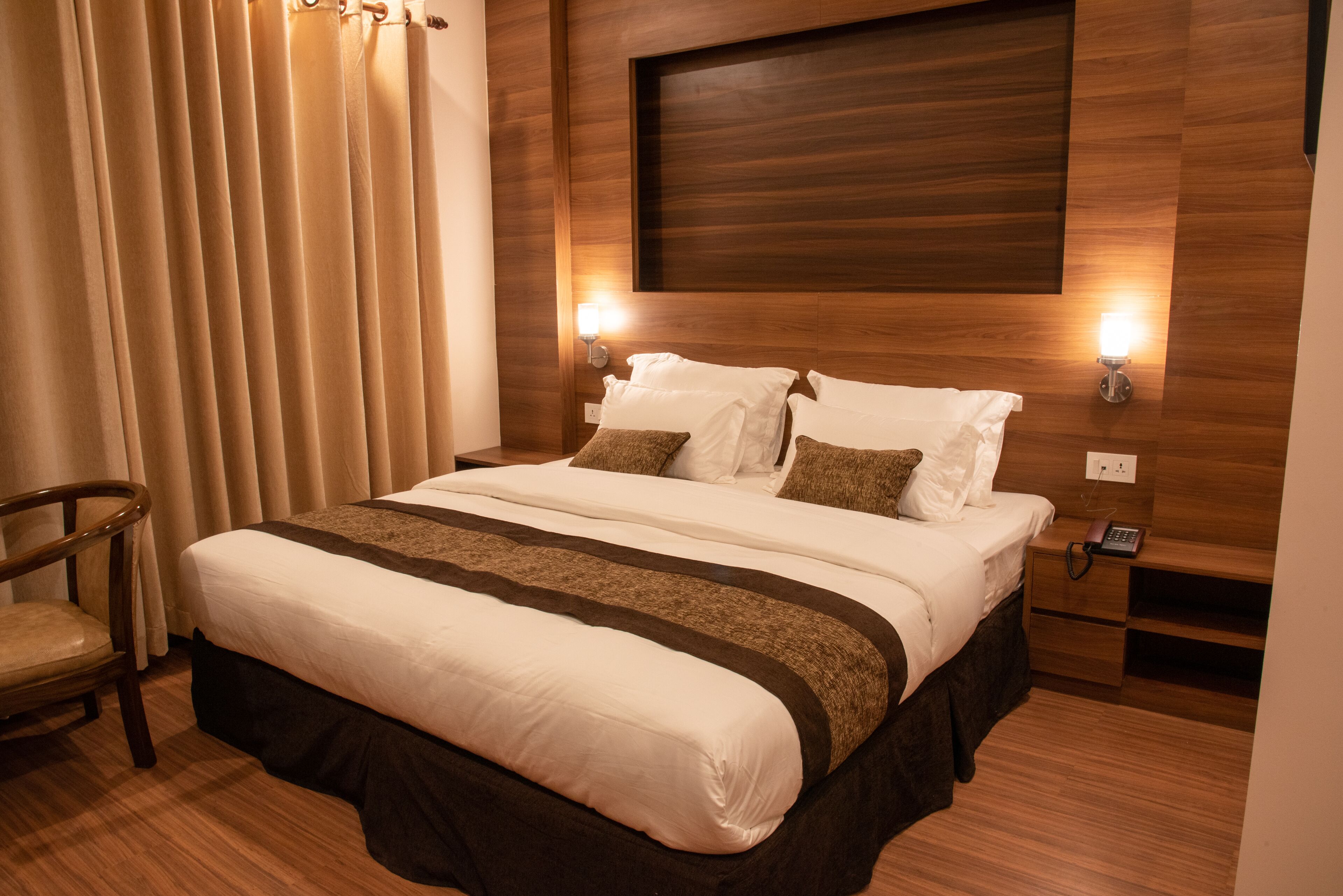 A neatly made bed with a brown and white bedspread, a wooden headboard, and two bedside lamps.