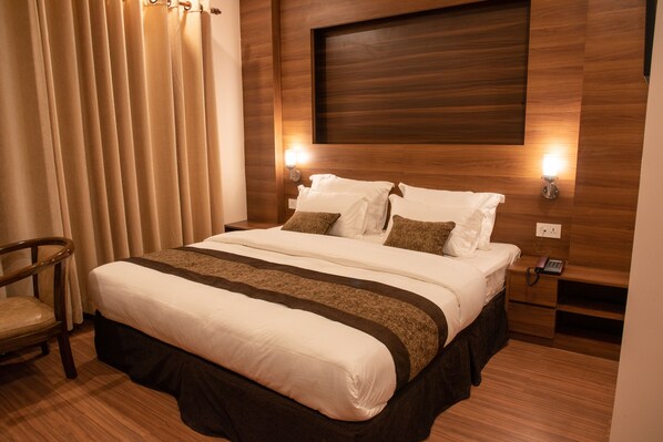 Un lit bien fait, recouvert d’une couvre-lit marron et blanche, avec une tête de lit en bois et deux lampes de chevet.