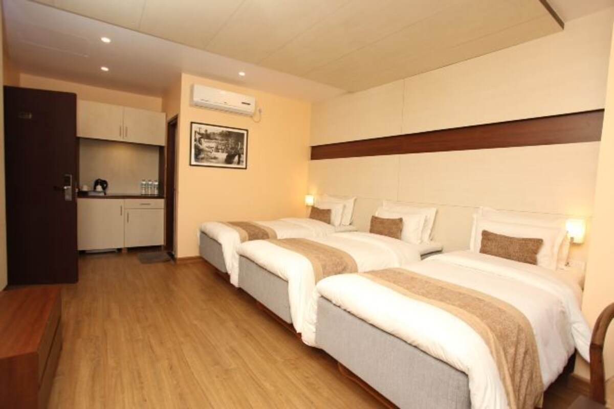 Una habitación de hotel con dos camas, kitchenette y un cuadro en la pared.