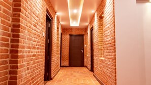 A hallway with brick walls and a patterned floor, leading to a door at the end. - Sunshine Boutique Hotel (Kathmandu)