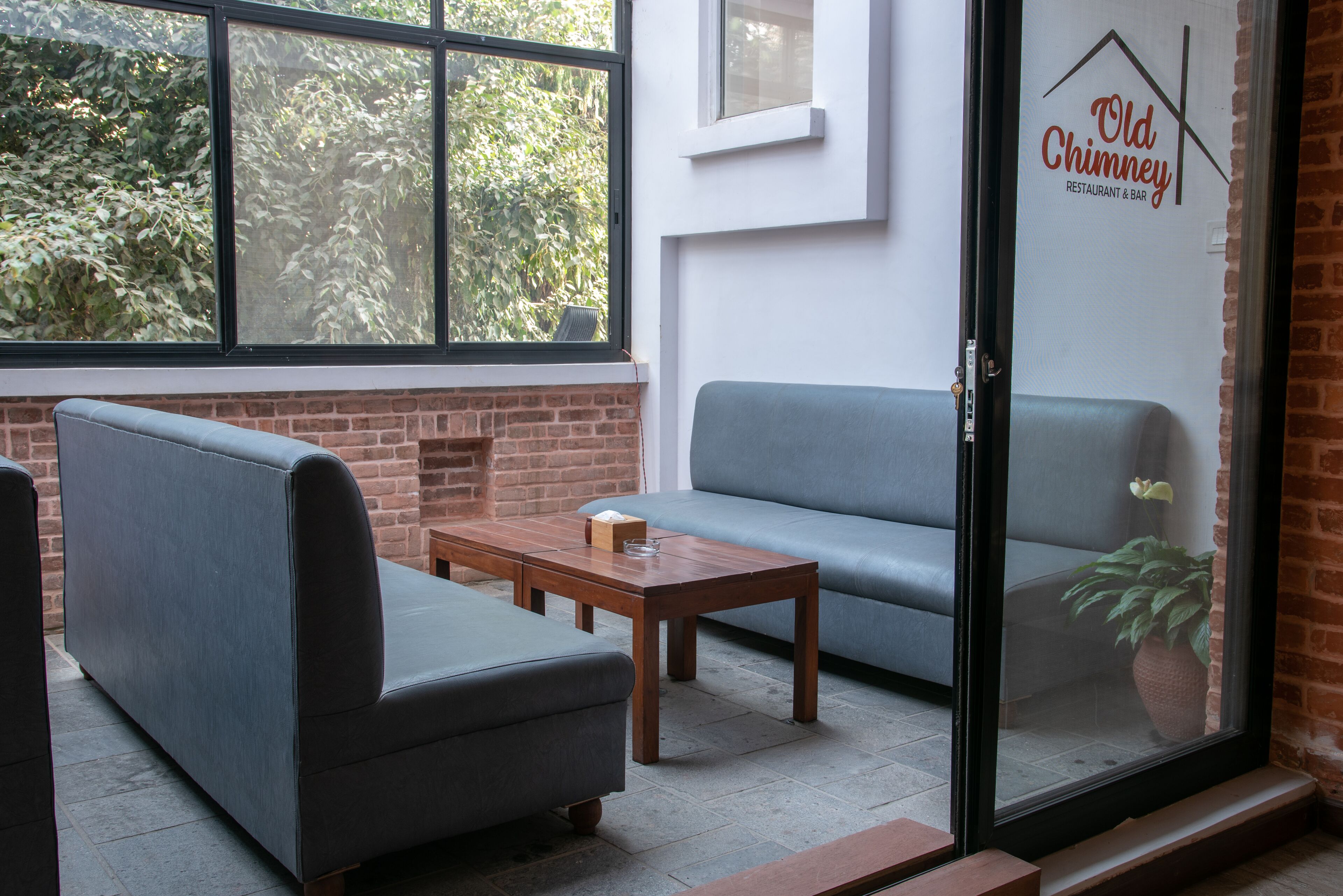 A modern interior with a brick wall, a grey sofa, a wooden coffee table, and a glass door with a logo.