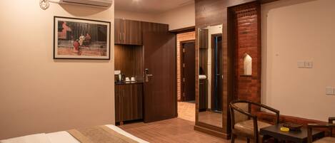 A hotel room with two beds, a small kitchenette, a mirror, and a dining area with chairs.