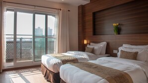 A hotel room with two beds, a large window with a view, and a wooden accent wall. - Sunshine Boutique Hotel (Kathmandu)