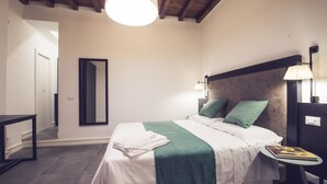 Une chambre à coucher bien rangée, avec un lit, des lampes de chevet, une petite table et un miroir au mur.
