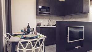 Une cuisine moderne avec des meubles de rangement aux couleurs sombres, un four à micro-ondes encastré et un téléviseur à écran plat.