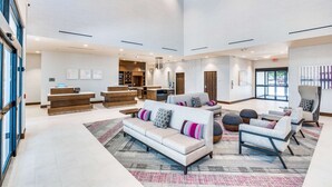 A spacious lobby with a reception desk, sofas, armchairs, and a large rug. - Hilton Garden Inn North Dallas Central Expy (Dallas)
