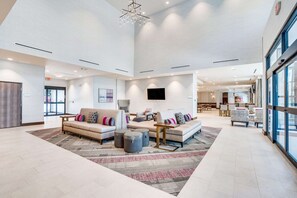 Un vestíbulo amplio con techo alto, muebles modernos y un gran ventanal que proporciona luz natural.