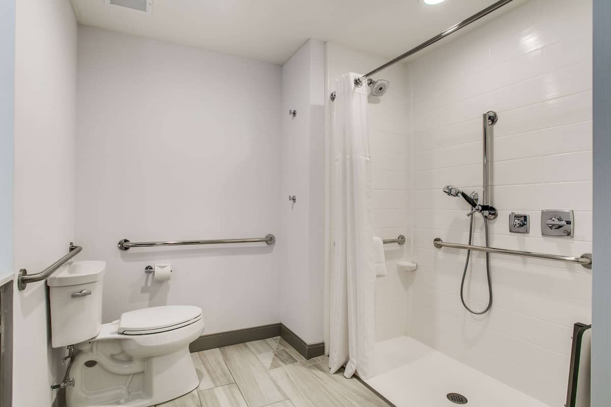 Een moderne badkamer met toilet, douche en handgrepen.