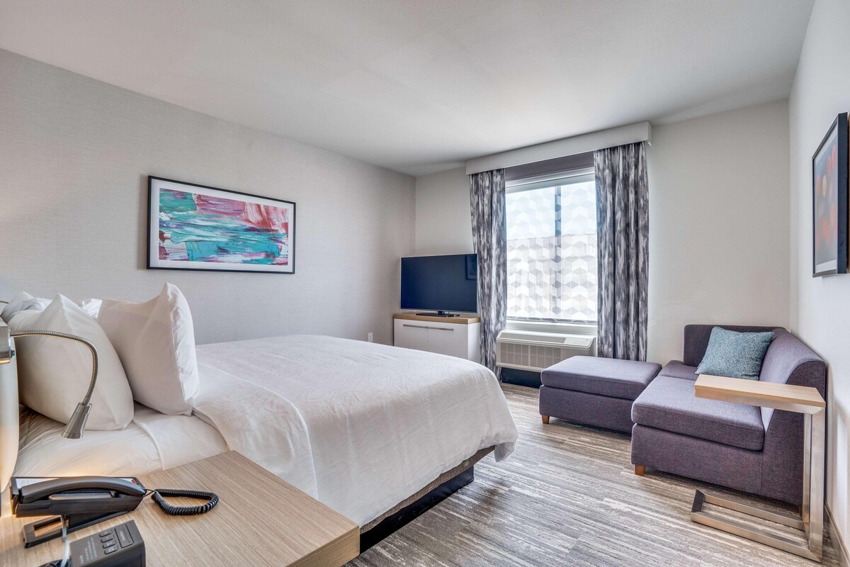 Une chambre d’hôtel avec un grand lit, un canapé, un bureau avec un téléphone et une télévision.